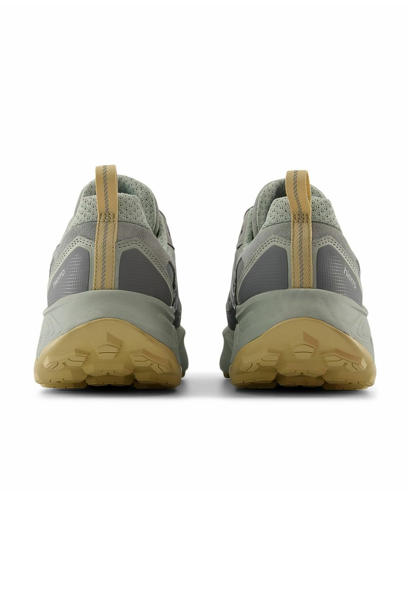 Paire de chaussures de randonnée grises et beiges avec semelles texturées, vues de dos, montrant les languettes de tirage au talon et les tiges en mesh respirant.