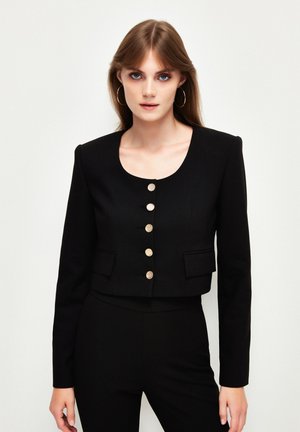 Černá zkrácená bunda s kulatým výstřihem, zlatými knoflíky vpředu a dvěma předními kapsami. Hladká tkanina a strukturovaný design.