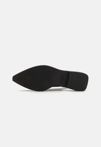 Semelle d'une chaussure à talons noirs, à bout pointu, texture lisse, avec une section plate au niveau du talon et un marquage minimal.