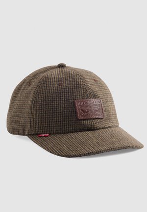Cappello a quadri marrone realizzato in tessuto testurizzato, con una patch in pelle marrone sul davanti e un piccolo etichetta rossa sul lato.