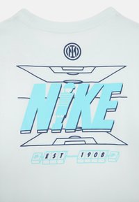 Svijetloplava pamučna majica s grafičkim printom koji prikazuje "NIKE" velikim blok slovima i "EST 1908," centrirano ispod kružnog logotipa.