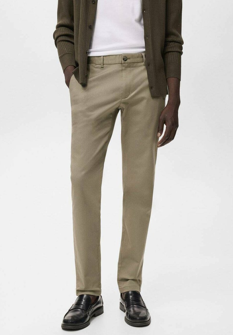 Kakhi chinos i bomullsblandning med rak bendesign, sidofickor och bakfickor, samt en klassisk knappstängning, kombinerat med svarta loafers.