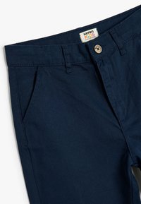 Pantalon pour enfants en coton bleu marine avec fermeture à bouton, passants de ceinture, poches avant et texture de tissu lisse et durable.
