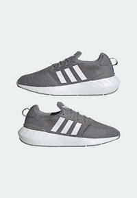 Gray Adidas sneakers with white soles and three white stripes, shown side by side on a light background.