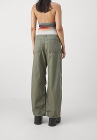 Zielone spodnie szerokie, wykonane z lekkiego materiału, z dwoma tylnymi kieszeniami i luźnym krojem, w połączeniu z tubą wielokolorową.