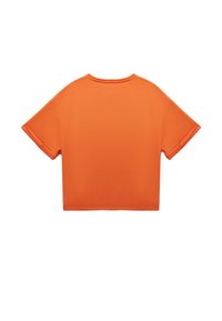 Camiseta corta de manga corta en tela de color naranja brillante, con cuello redondo y mangas enrolladas, textura suave sin patrones.