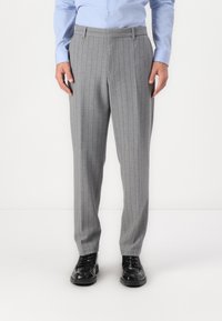 Pantalones gris claro a rayas con un corte recto, con una textura suave y pliegues frontales, combinados con zapatos negros de cordones.