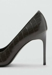 Zwarte lakleren pump met hoge hak, krokodillenhuidtextuur, puntige neus en een slanke, stilettohak.