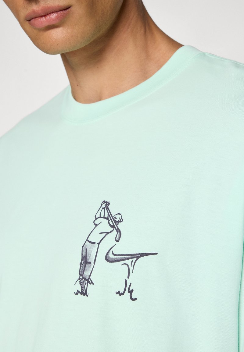 Mint green t-shirt made of soft fabric, featuring a graphic of a golfer in black and a curved line symbol below the figure.