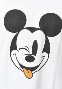 Hvid bomulds T-shirt med et stort sort-hvidt grafik af en smilende tegneseriefigur med overdimensionerede sorte ører og en orange tunge.