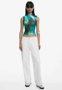Fitted sleeveless top in teal and brown tie-dye, paired with wide-leg white jeans. Accessories include sleek black sunglasses and a silver arm cuff.