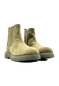 Botas de tobillo de ante marrón con paneles laterales elásticos y suelas de goma texturizada. Punta redondeada y diseño minimalista.