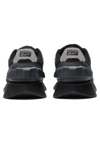 Scarpe da ginnastica nere e grigie con una tomaia testurizzata, una suola ammortizzata e un marchio prominente sul tallone.