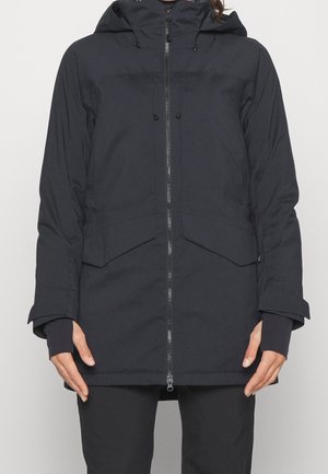 Czarna zimowa kurtka z kapturem z przednim zamkiem błyskawicznym, kieszeniami z patkami i mankietami z otworem na kciuk, noszona przez osobę z rękami swobodnie opuszczonymi wzdłuż ciała.