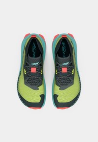 Scarpe da trail running con una tomaia in maglia verde, accenti grigio scuro, suola leggera, dettagli rossi e teal, e modelli di grip testurizzati.