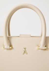 Beige leather handbag with two rounded handles, gold-tone hardware, and a decorative bee emblem on the front. Smooth texture, minimalist design.