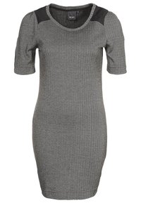 Šaty délky ke kolenům s černobílým herringbone vzorem, krátkými rukávy a černými decentními akcenty na ramenech. Přiléhavý střih s kulatým výstřihem.