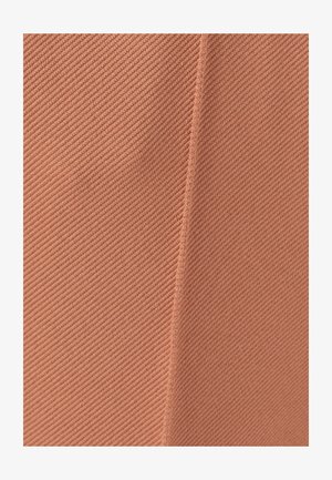 Tissu texturé dans une teinte corail douce et atténuée, présentant des crêtes diagonales et un détail de couture, suggérant un design structuré et un matériau léger.