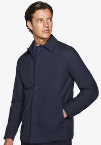 Marineblå letvægtsjakke lavet af glat stof, med krave, knaplukning og sidelommer. Minimalistisk design med rene linjer.