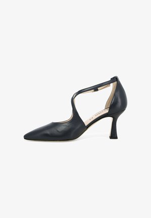 Decolleté da donna in pelle nera con punta affilata, tacco medio curvo e cinturino a incrocio alla caviglia su sfondo bianco.