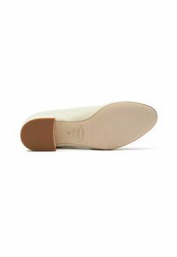 Zapato plano beige con parte superior de cuero suave, punta redondeada y suela de goma baja y gruesa. Presenta un sutil logo de la marca en la plantilla.