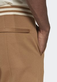 Bruna vävda byxor med strukturerad finish, med en elastisk midjeresår med krämfärgade ränder och sidofickor, skräddarsydd passform.