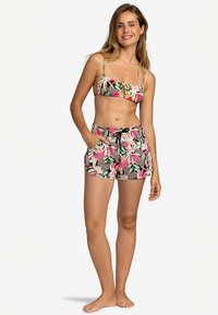 Tweedelige badkledingset met een bloemenpatroon in roze, groen en zwart. Het topje heeft dunne bandjes en het broekje is elastisch met een trekkoord.