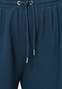 Mörkblå träningsoverallbyxor med elastisk midja, justerbar dragsko, silverfärgade öglor och mjukt bomullstextur.