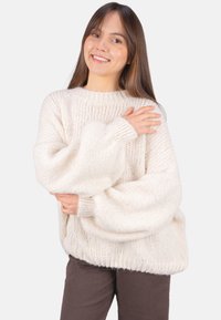 Übergroßer gestrickter Pullover in cremefarben mit strukturierter Oberfläche, weiten Ärmeln sowie gerippten Bündchen und Saum. Legerer Schnitt, ideal zum Übereinandertragen.
