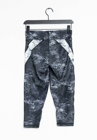 Černobílé legíny se vzorem a lesklým povrchem, s bílými bočními panely a pohodlným střihem, zavěšené na černém háčku.