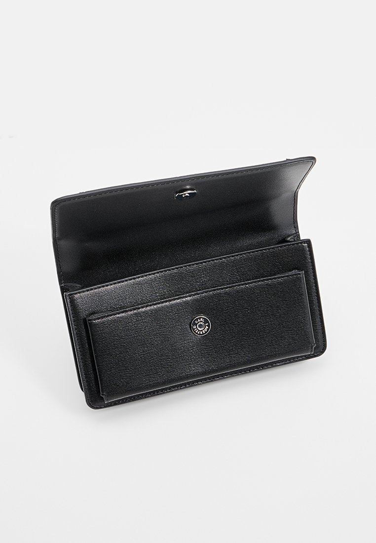 Portefeuille en cuir Noir avec fermeture à pression, ouvert pour montrer le compartiment intérieur et la poche avant avec un détail de bouton de marque.