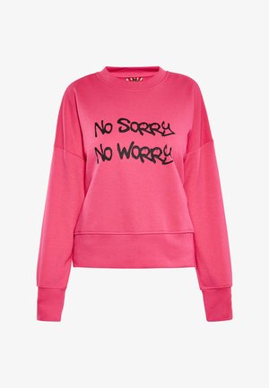 Różowy sweter z okrągłym dekoltem i długimi rękawami, z czarnym tekstem w stylu graffiti "No Sorry No Worry" z przodu. Miękki, casualowy design.