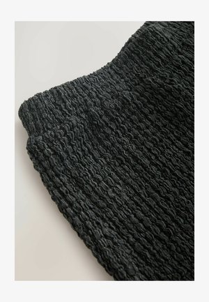 Black textured fabric with a crinkled design and soft surface, showcasing a wave pattern. Edges are smooth and slightly curved.