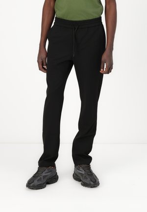 Pantaloni de jogger negri cu talie elastică și șnur. Construiți dintr-un material moale, dispun de buzunare laterale și un design cu picior conic.