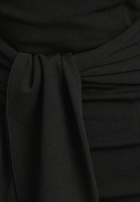 Čierne šatky z látky s detailom viazania v páse, s jemnou textúrou a skladmi. Dizajn zdôrazňuje hladký, elegantný siluetu.