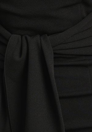 Abito di stoffa nera con dettaglio in vita annodato, caratterizzato da una texture morbida e delle pieghe. Il design mette in risalto una silhouette liscia ed elegante.