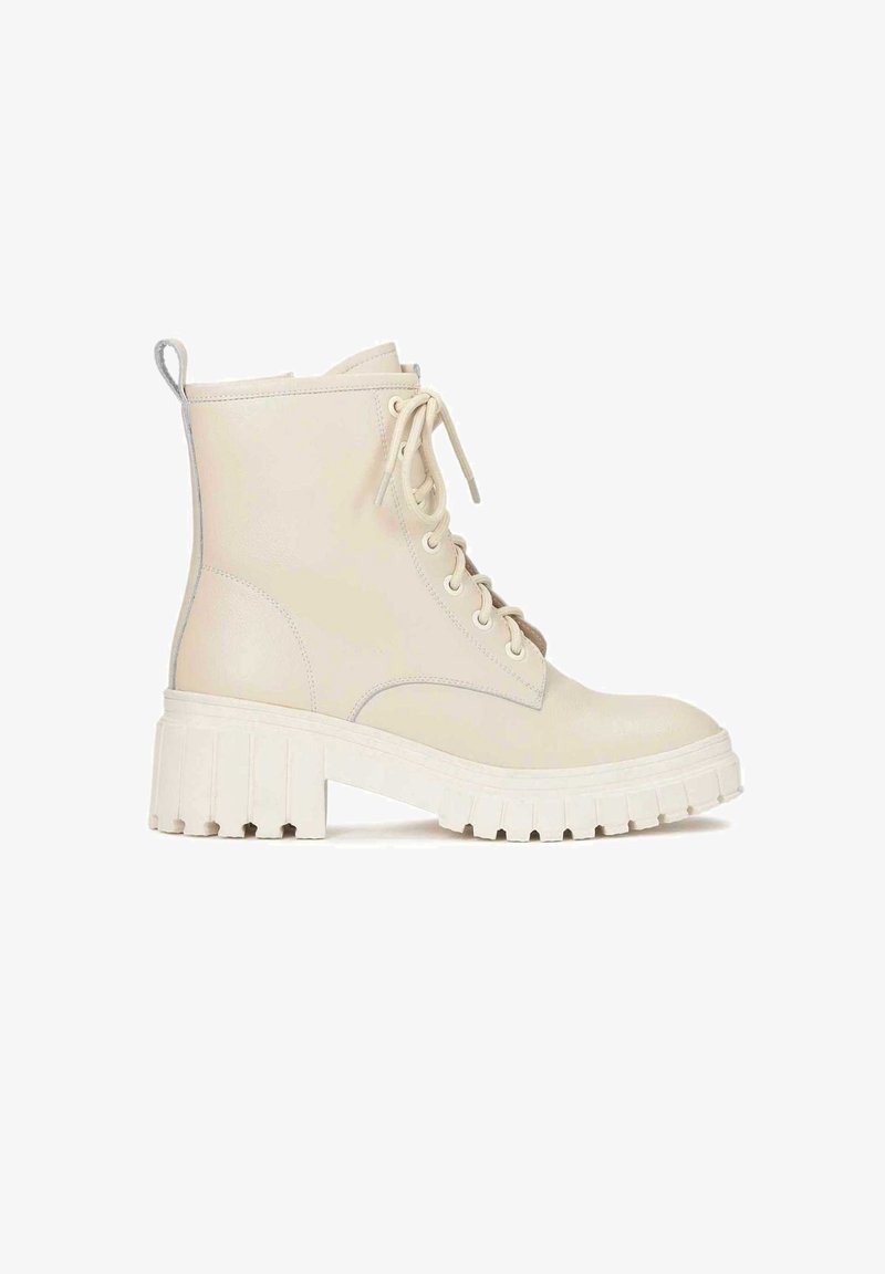 Cream ankle boot made of smooth leather, featuring a sturdy white chunky sole, round toe, and front lace-up closure with metal eyelets.