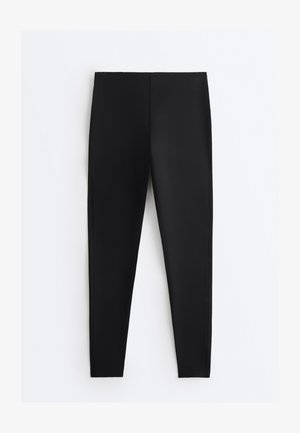 Musta, korkea vyötäröinen legginsit, joissa on kapea istuvuus ilman näkyviä saumoja tai taskuja, esitettynä tasaisesti valkoisella taustalla.