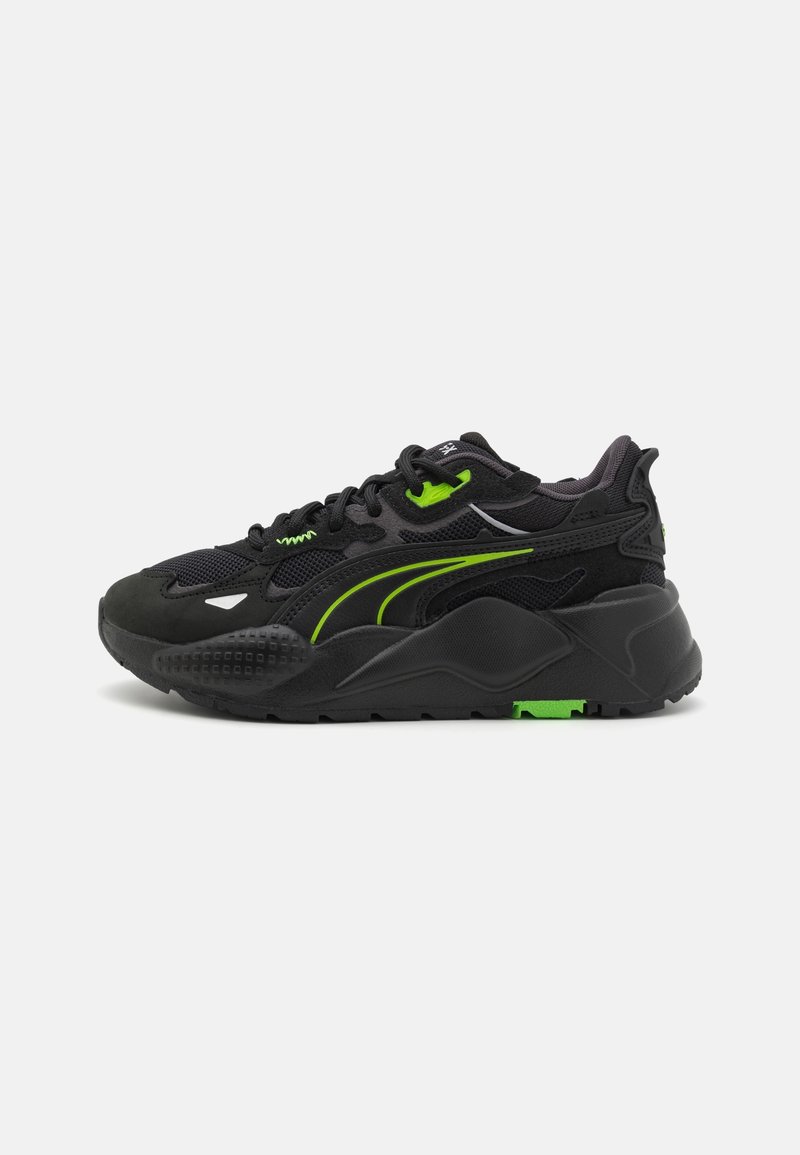 Baskets de sport noires avec des accents vert néon, semelle épaisse et matériaux en mesh et en suède, vues de côté sur un fond uni.