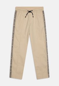 Beige joggingbroek met een elastische tailleband en een zwart trekkoord. De zijnaden hebben een zwart-wit "HILFIGER" logo bandaccent.