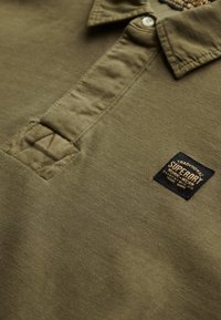 Olijfgroene polo shirt van katoen, met een knoopsluiting aan de kraag, een label met het merkteken en gestructureerde accenten op de knoopsluiting.
