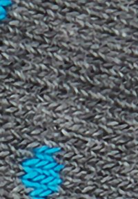 Grauer Strickstoff mit strukturiertem Muster, durchsetzt mit blauen Akzenten, die einen visuellen Kontrast bieten.