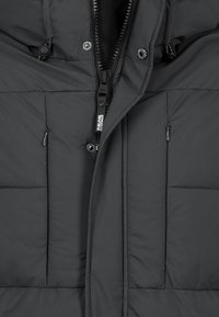 Black puffer jacket with a zip closure, featuring two front pockets and textured fabric. Inside lining is visible around the collar.