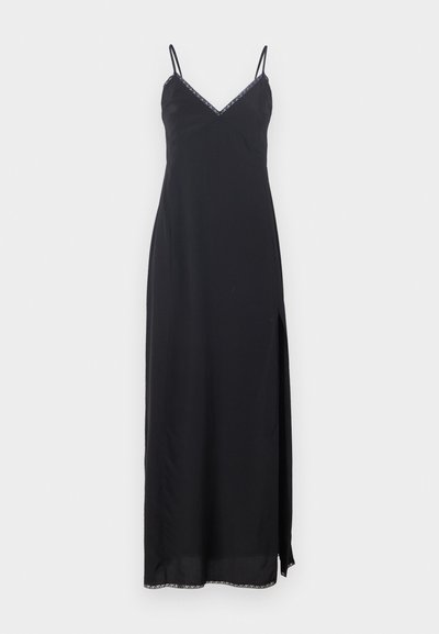 Melnas slīdējošās kleitas ar plāniem siksniņām, V veida izgriezumu, sānu šķēlumu un dekoratīvu apdari ap izgriezumu un apakšmalu. Izgatavota no viegla materiāla.