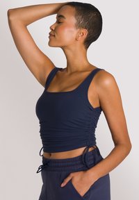 Canotta blu navy a costine con dettagli di arricciatura laterale regolabili. Abbinata a joggers coordinati con tasche laterali.