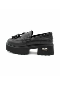 Zwarte leren loafers met een chunky plateauzool, decoratieve kwastjes en gestikte details. Zilveren accenten aan de zijkant.