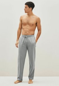 Pantalones de chándal grises hechos de una tela suave, con una cintura elástica con cordón, piernas rectas y una textura lisa.