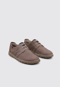 Zapatos informales marrones con detalles perforados, diseño de cordones, textura suave y una suela de goma contrastante con manchas beige.