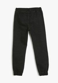 Pantalones jogger de mezclilla negra con cintura elástica y puños fruncidos. Textura suave y diseño de pierna ajustada. Sin bolsillos visibles.