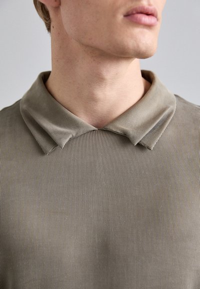 Khaki riipikuva pullover, jossa on litteä, pehmeä kaulus. Kangas on teksturoidulla, pystysuoralla kuviolla ja se istuu tiiviisti kaulan ympärillä.